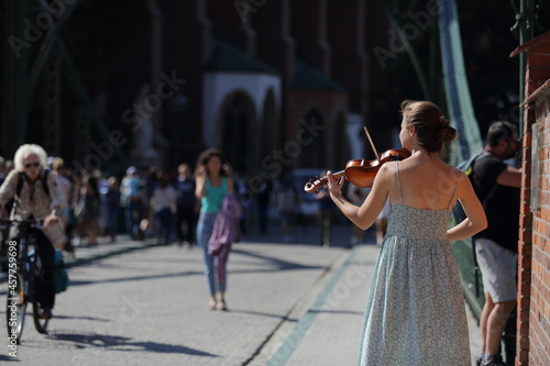Piękna moda dziewczyna, skrzypaczka gra na skrzypcach na moście we Wrocławiu.