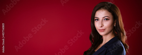 Business beautiful woman in suit posing on red background
