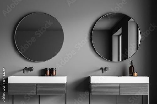 Dark grey bathroom vanity area with two round mirrors