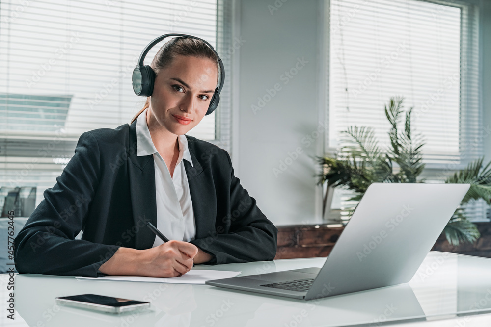 Businesswoman wearing formal suit is sitting at workplace and li - obrazy, fototapety, plakaty 