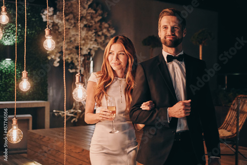 Beautiful young couple in formalwear spending time on night party photo