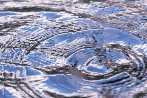 Large drops of rain on the water leaves waves.