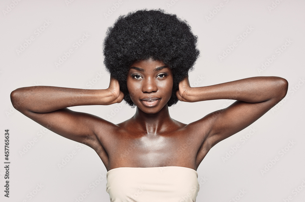 Portrait of beautiful young African woman covering ears with hands while standing against gray background Portrait of beautiful young African woman covering ears with hands while standing against gray background