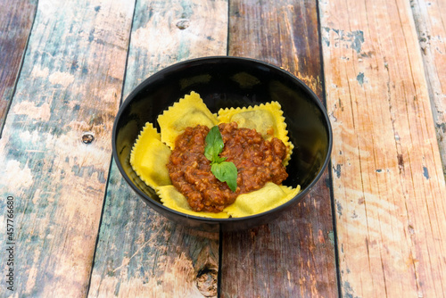 Delicious meat filled ravioli with bolognese sauce and basil leaves on top