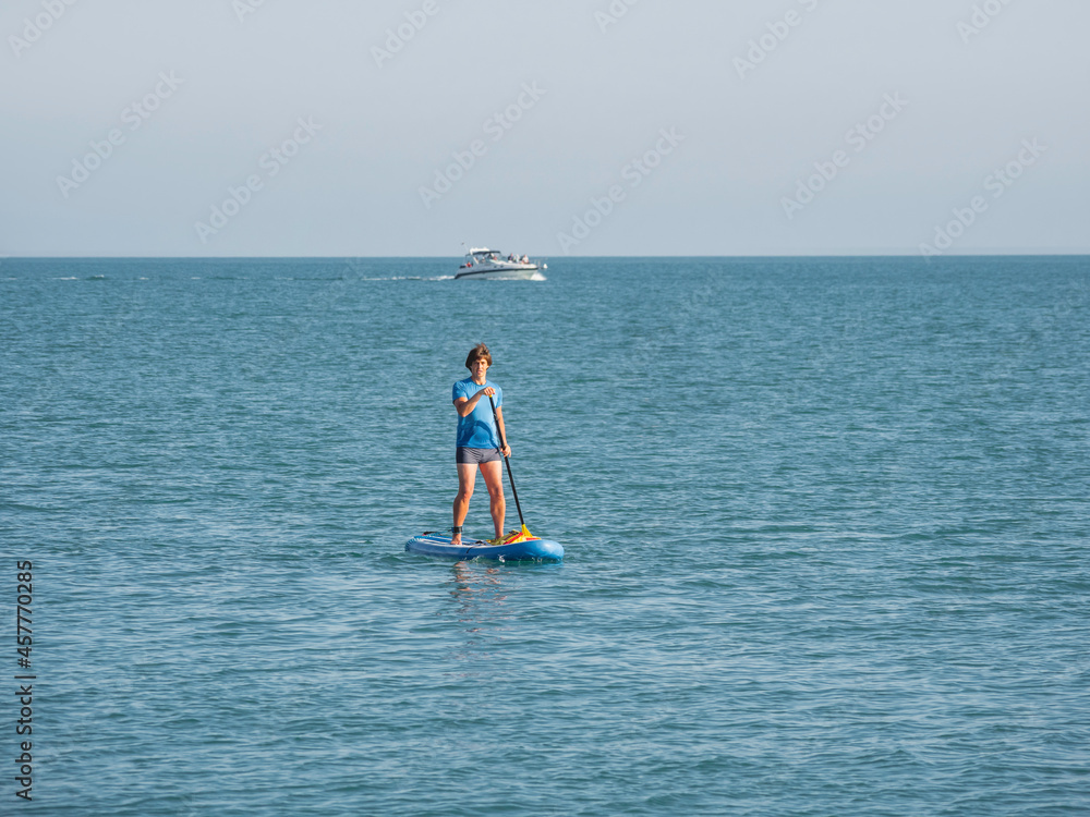 Naklejka premium Paddle boarder. Sportsman paddling on stand up paddleboard. SUP surfing. Active lifestyle. Outdoor recreation. Vacation on seaside.