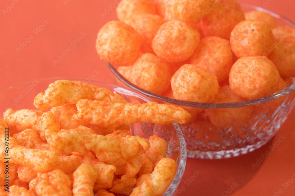 Orange cheese snacks in glass pots on an orange surface Orange cheese snacks in glass pots on an orange surface