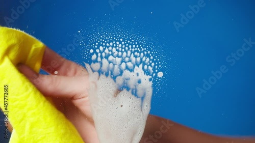 Hand spraying on window with detergent from dispenser, house cleaning and washing. Woman wiping with red cloth. Housekeeping, using spray with liquid soap. Antibacterial disinfectant, covid protection