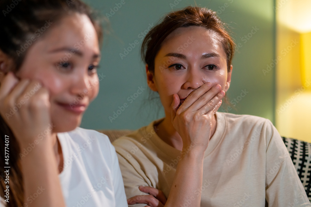 Millennial Asian woman friends sitting on sofa watching drama movie on tv with crying together in living room. Female friendship enjoy and having fun weekend activity lifestyle with home entertainment Millennial Asian woman friends sitting on sofa watching drama movie on tv with crying together in living room. Female friendship enjoy and having fun weekend activity lifestyle with home entertainment