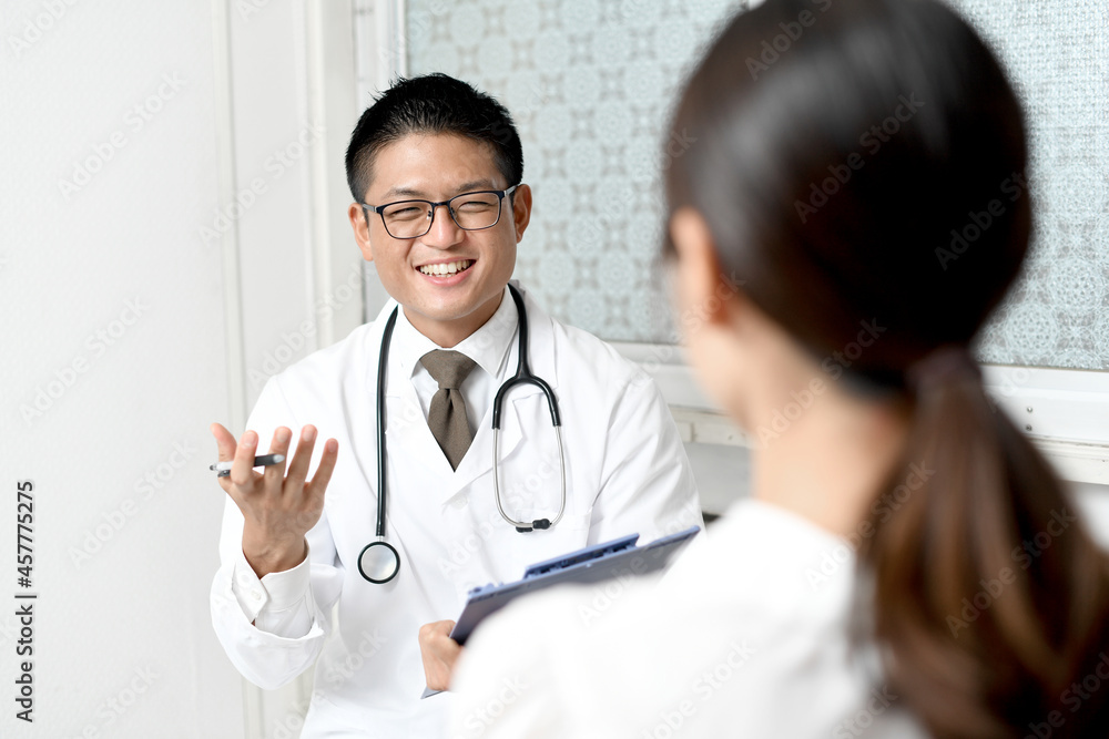 Fototapeta premium 問診をする白衣を着た笑顔の若い男性医師（医療従事者・ドクター）