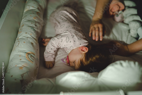 Bilde på lerret Small caucasian baby going to sleep hands of unknown woman mother putting blanke