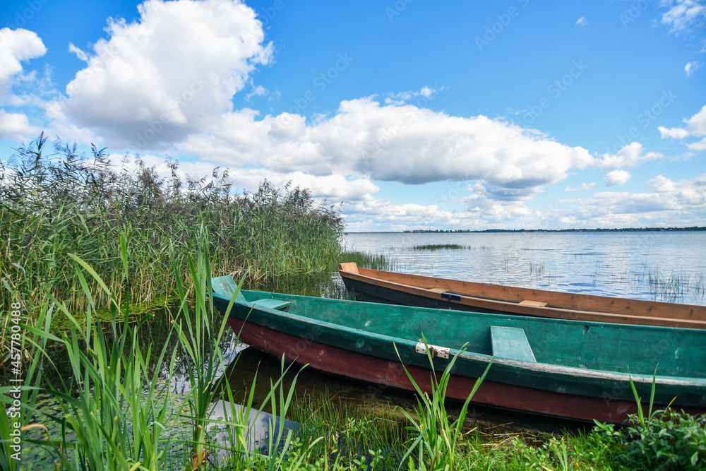 Wooden fishing boat on the lake with transparent blue sky and clear water