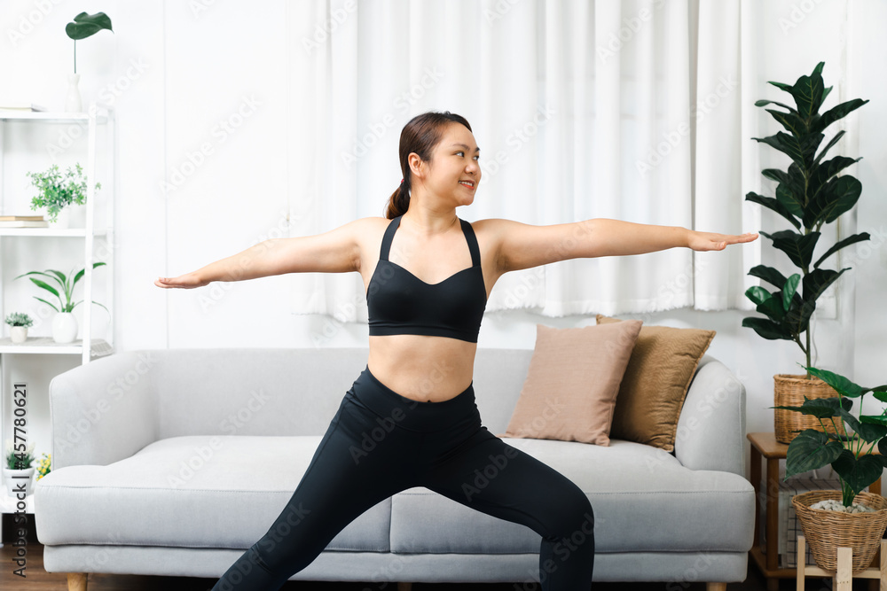 Portrait of gorgeous young asian woman practicing yoga at home stretching out while following a yoga routine Portrait of gorgeous young asian woman practicing yoga at home stretching out while following a yoga routine