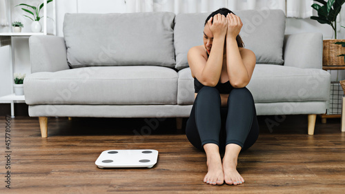 Foto Asian woman with scales bored of dieting Weight loss fail Upset on weight scale