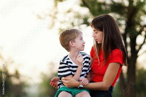 Candid authentic family portrait outdoor. Casual mom with her son in confidential conversation In Rural Settings. Young woman with child on countryside background