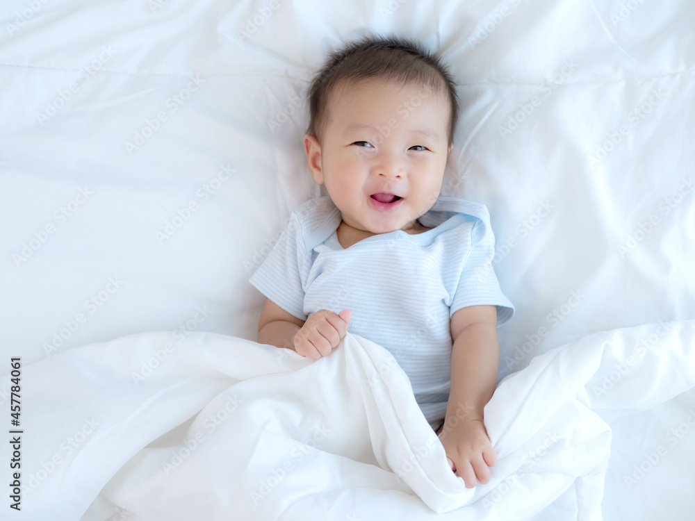 Happy smiling of adorable Asian baby girl on a white bed , happy healthy baby girl for bed time concept Happy smiling of adorable Asian baby girl on a white bed , happy healthy baby girl for bed time concept