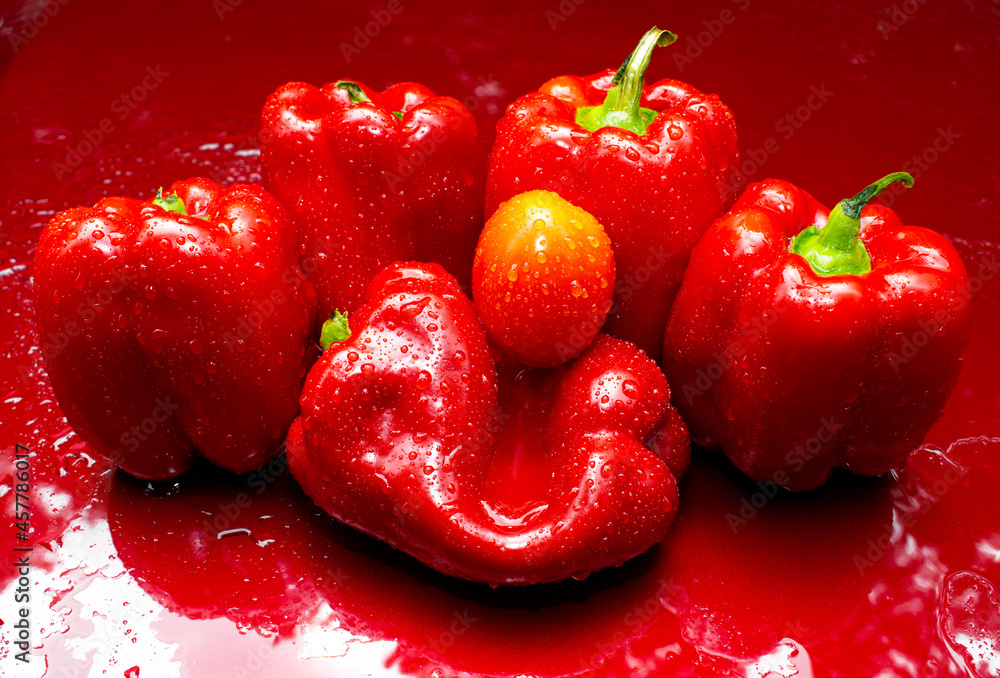 Red Bell Peppers with one Tomato on a red background Red Bell Peppers with one Tomato on a red background