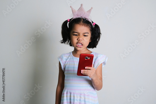 Asian little girl looking to her mobile phone with annoyed face expression