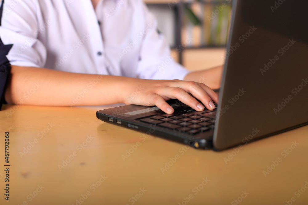 A young girl sits at a computer in the office. Schoolgirl in a laptop studies remotely. Office worker in an office with gadgets. Online training. Young teacher preparing for lessons A young girl sits at a computer in the office. Schoolgirl in a laptop studies remotely. Office worker in an office with gadgets. Online training. Young teacher preparing for lessons