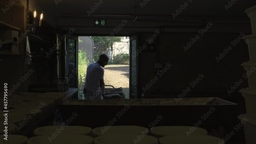 Picture in picture, man walking in the bakery with a hand truck full of wood, preparing the oven for the bread Picture in picture, man walking in the bakery with a hand truck full of wood, preparing the oven for the bread