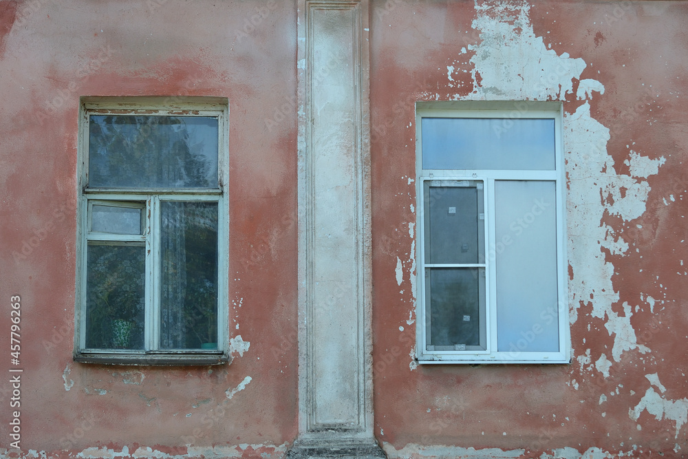 Two windows on an old pink painted and tattered wall