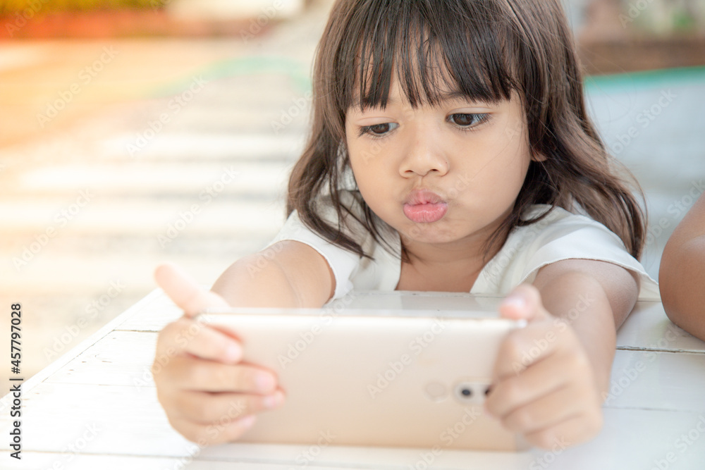 Little Asian girl using smart phone at cafe. Natural light outdoor lifestyle. Little Asian girl using smart phone at cafe. Natural light outdoor lifestyle.
