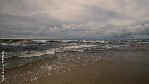 Waves on a sandy Baltic beach in a storm. Clouds over the horizon at the end of a summer day in Latvia. Long deserted beach in Vidzeme. Latvia photo