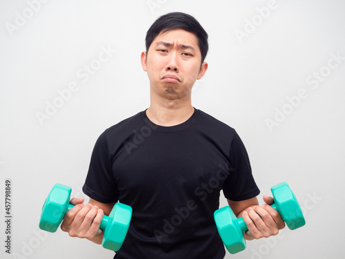 Man holding drumbbell feeling bored to workout sad emotion