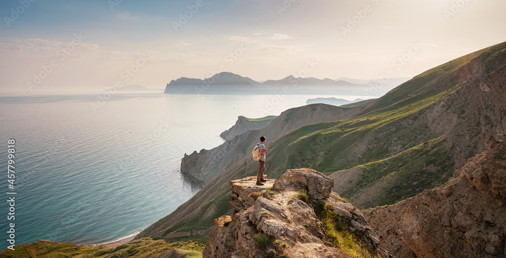 Young man travels alone on the backdrop of the mountains enjoy view of beautiful landscape natural mountain with sea, the lifestyle concept of traveling outdoors.