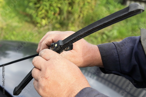 Replacement of car wiper blade, DIY seasonal vehicle maintenance service, male hands close-up on the background of green grass