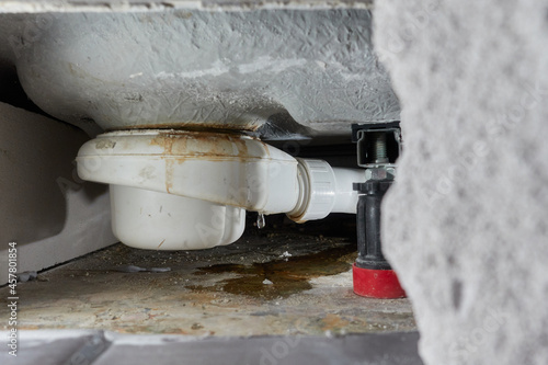 Leaking siphon of a shower tray in the bathroom, causes water damage. Tiles and masonry were removed for repair and construction drying. The cause is incorrect installation or clogging of the pipe.