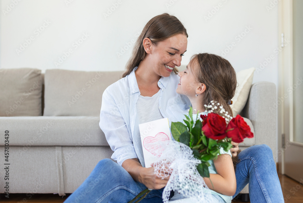 Happy mother's day! Child daughter congratulates mom and gives her postcard and flowers. Mum and girl smiling and hugging. Family holiday and togetherness. Happy mother's day! Child daughter congratulates mom and gives her postcard and flowers. Mum and girl smiling and hugging. Family holiday and togetherness.
