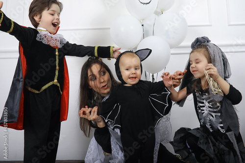 Happy family with children in costumes of witch and vampire in a house in holiday Halloween