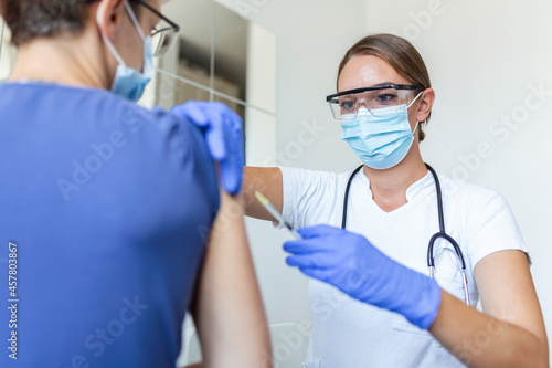 General practitioner vaccinating old patient in clinic with copy space. Doctor giving injection to senior man at hospital. Nurse holding syringe before giving Covid-19 or coronavirus vaccine.
