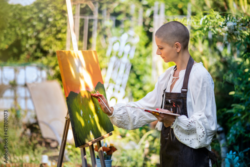 Fotobehang Beautiful young woman relaxing while painting an art canvas outdoors in her garden