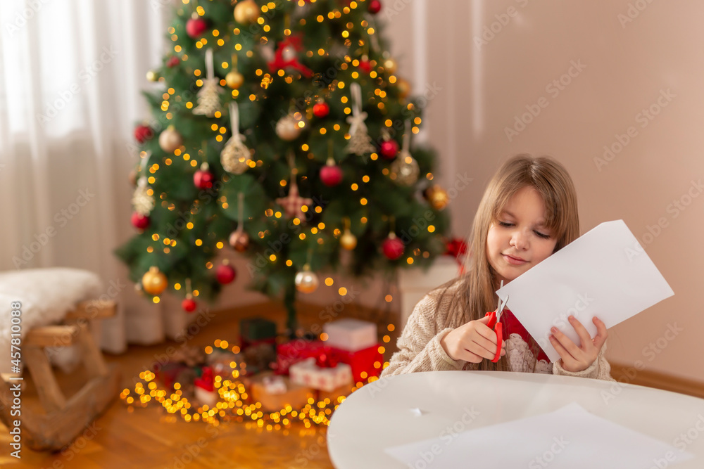 Little girl cutting out paper Christmas decorations Little girl cutting out paper Christmas decorations