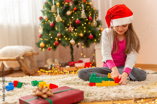 Little girl playing by the Christmas tree