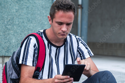 young student with backpack using digital tablet