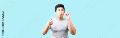 Asian man does a self test for covid 19 on blue background in studio, Coronavirus nasal mucosa test for infection with a medical cotton swab.