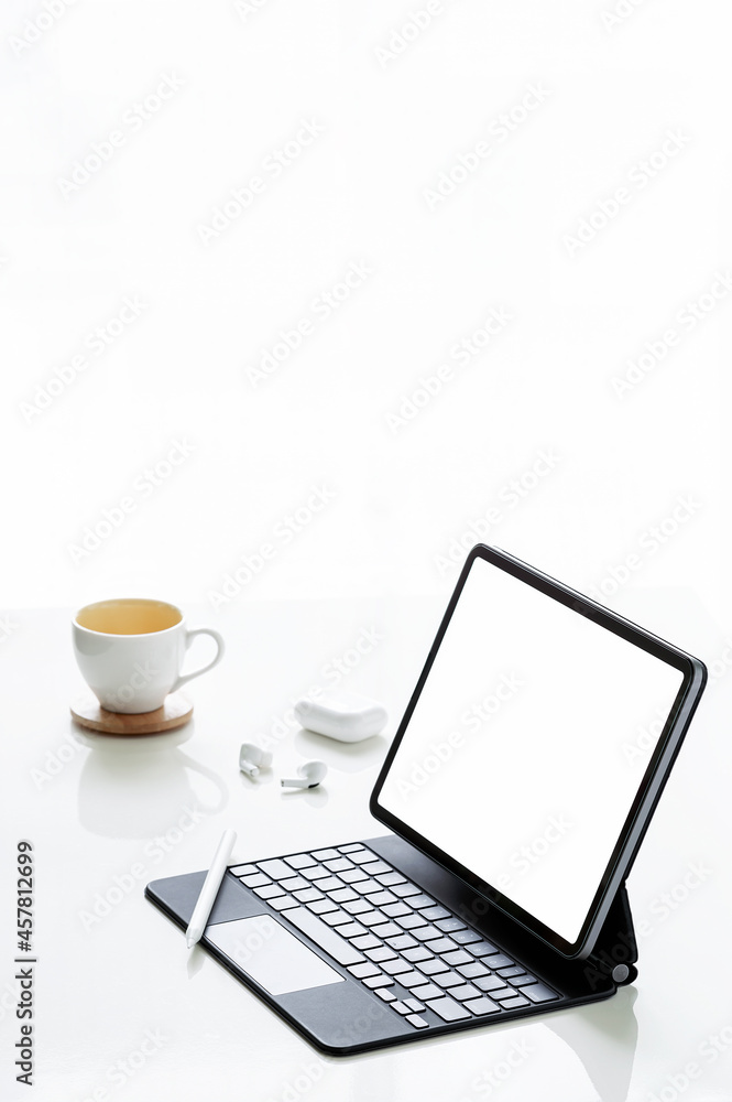 Blank screen tablet with magic keyboard, coffee cup and earphone on whilte background, vertical view. Blank screen tablet with magic keyboard, coffee cup and earphone on whilte background, vertical view.