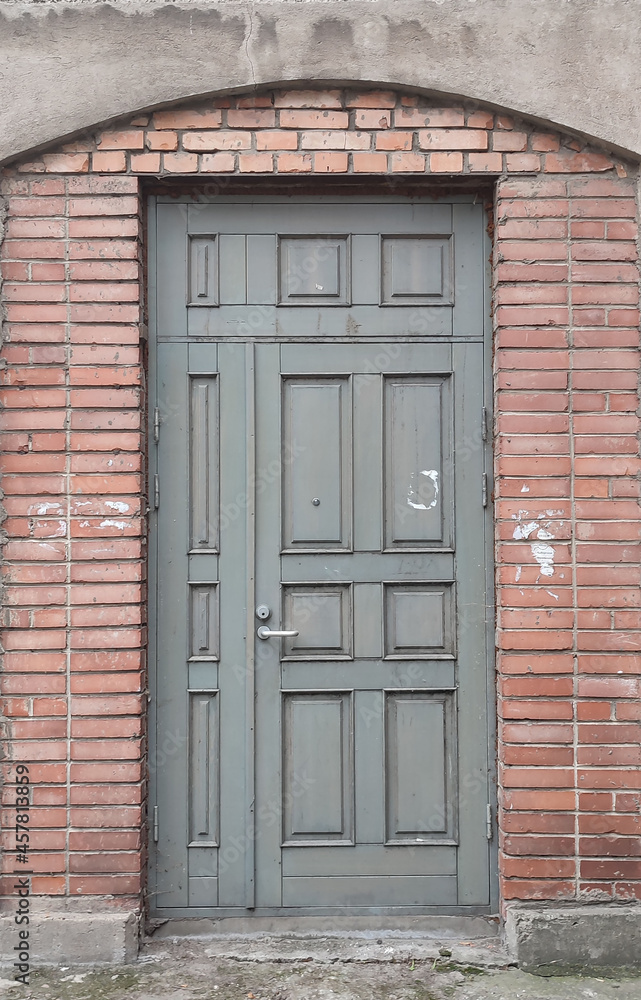 Old gray wooden door in red brick wall, empty abstract interior, vertical background texture