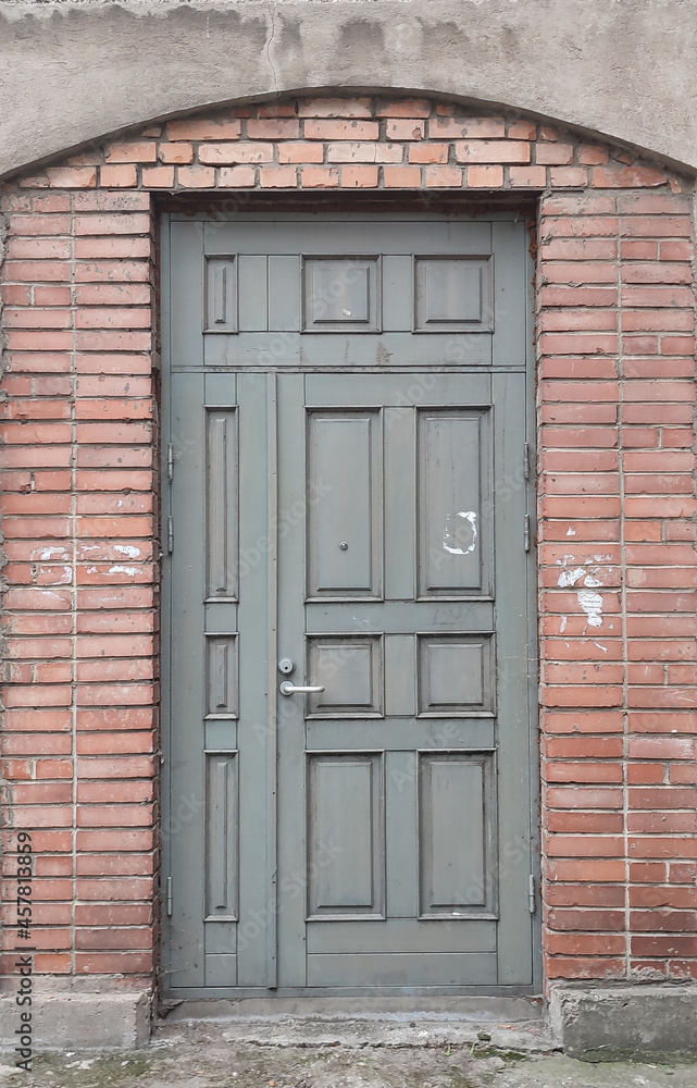 Old gray wooden door in red brick wall, empty abstract interior, vertical background texture Old gray wooden door in red brick wall, empty abstract interior, vertical background texture