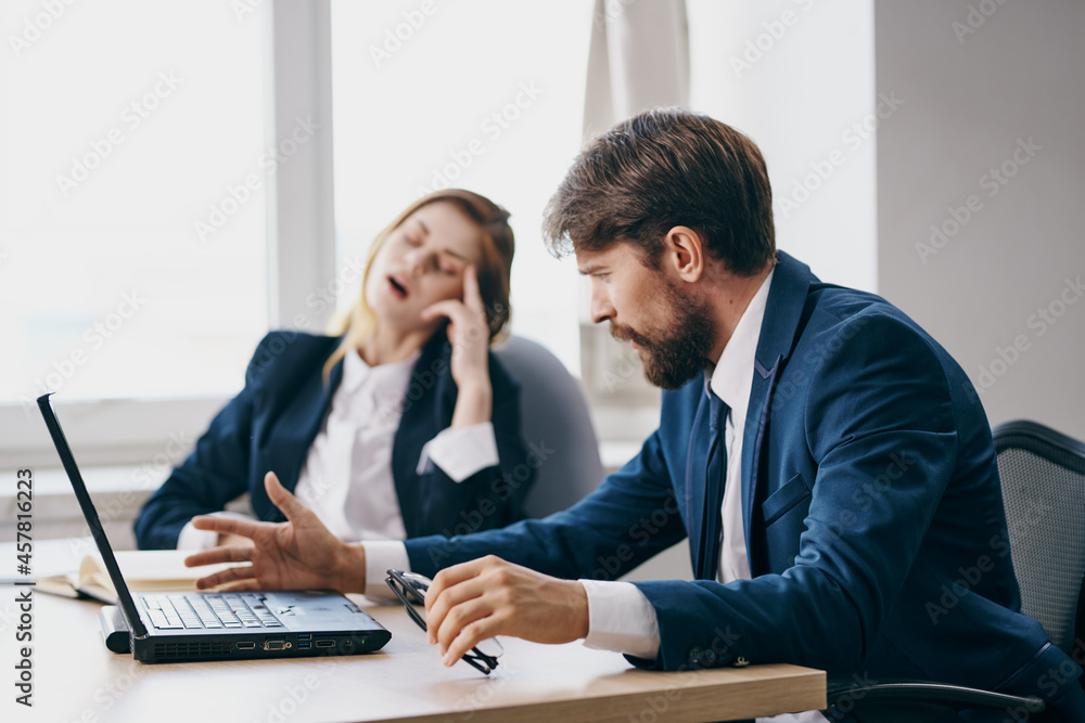 Fototapeta premium business man and woman sitting at a desk with a laptop communication officials