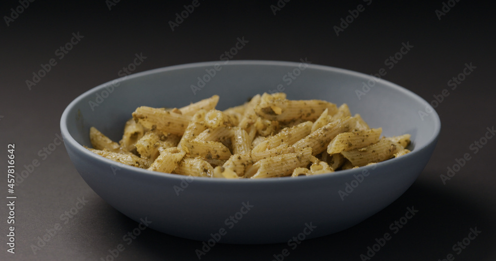 pesto penne in blue bowl on black background pesto penne in blue bowl on black background