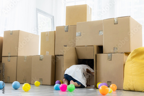 Daughter playing with parcel cardboard. Relaxing in living room in the house. Happy family enjoying relocation