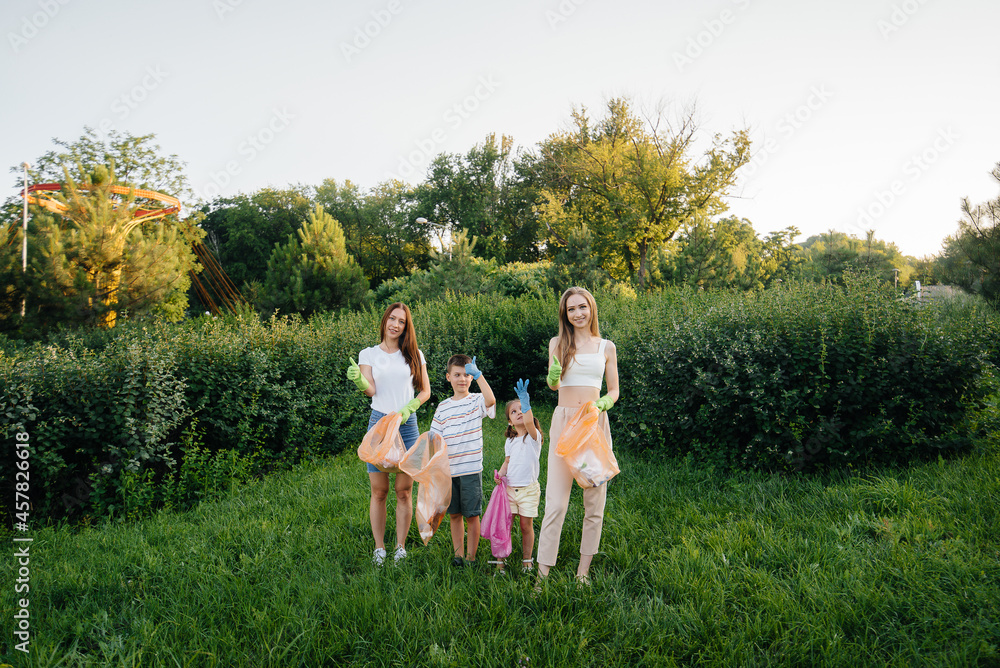 Obraz premium A group of girls with children at sunset are engaged in garbage collection in the park. Environmental care, recycling.