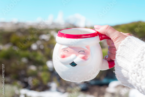 Close up view of one hand holding a cup of coffee on the snow winter day background. Volcano Teide behind the scene. Tenerife
