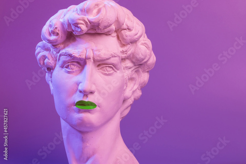 Gypsum copy of the sculpture David Michelangelo with green lips on purple background