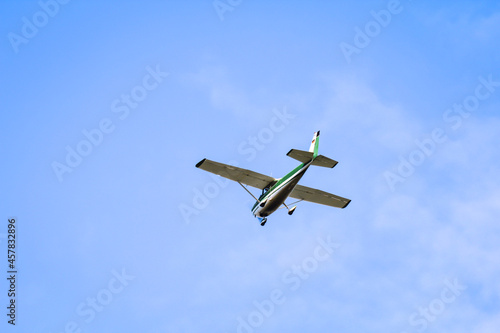 Ein kleines Propeller betriebenes Flugzeug am Himmel über einem Flugplatz.