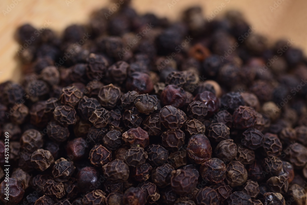 Black peppercorns on a wooden bowl on a white background. Food. Spices. Black peppercorns on a wooden bowl on a white background. Food. Spices.