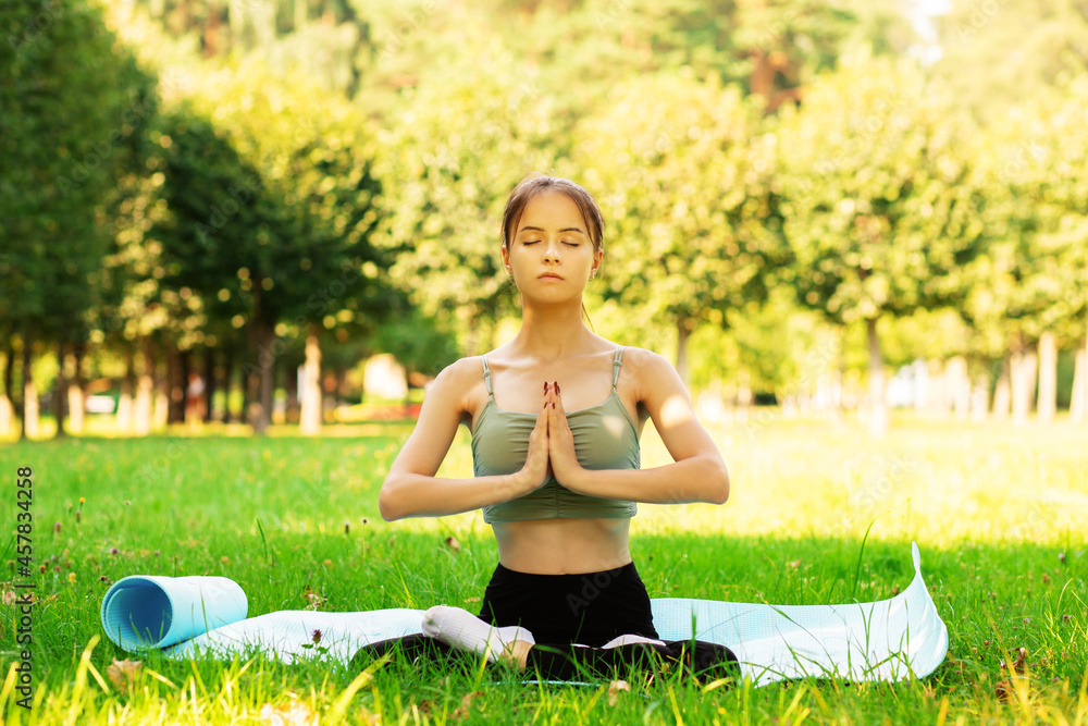 teenager yoga outside,young girl in the park is sitting in the lotus position, a girl in nature, health outdoor